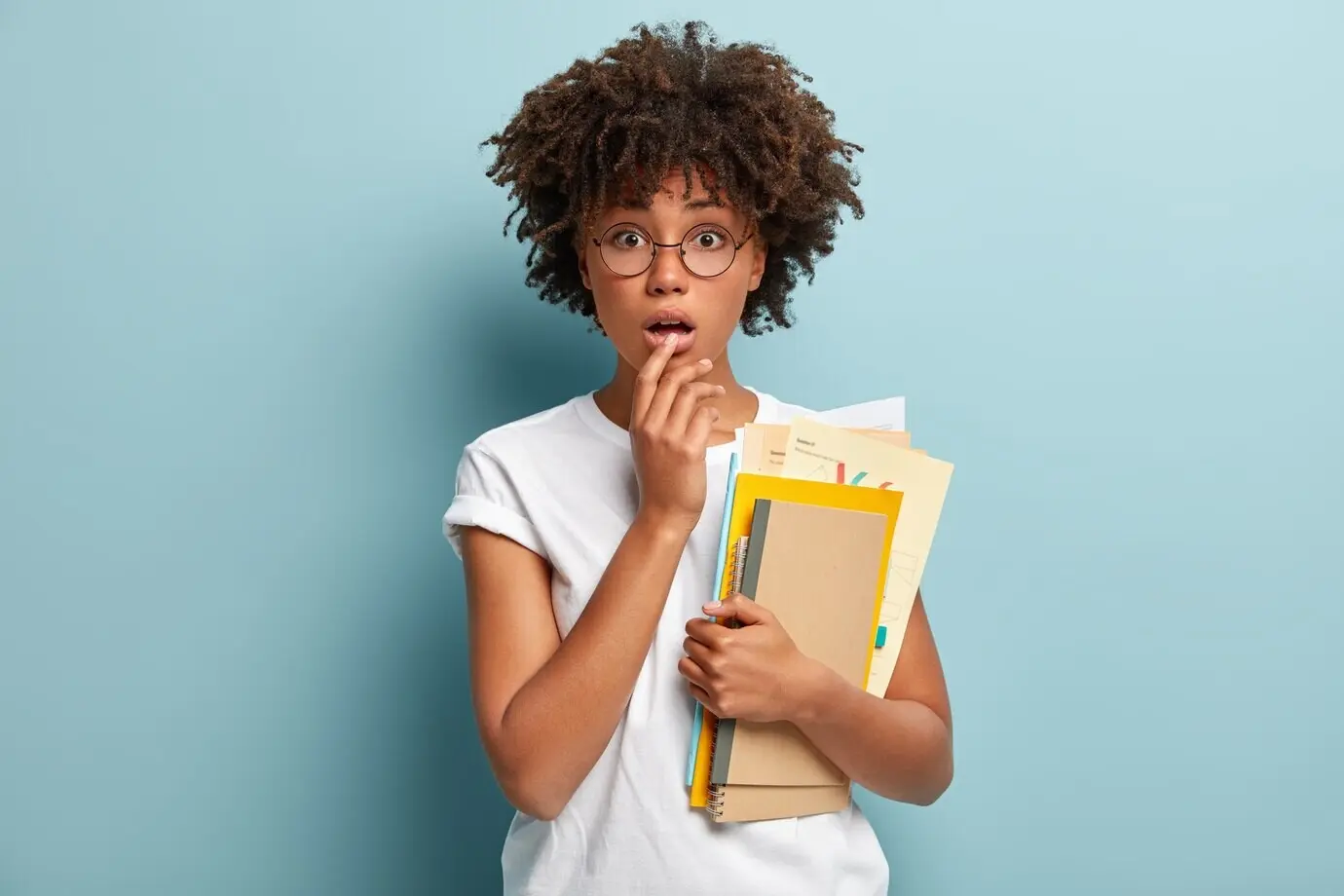 Horizontale Aufnahme einer schockierten jungen Frau, die die Hand an die Lippen hält und überrascht blickt.