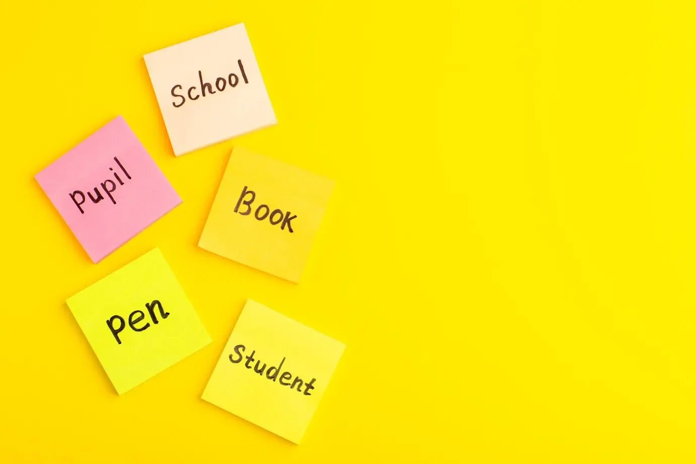 Draufsicht auf verschiedene Aufkleber mit Wörtern darauf, über einer gelben Oberfläche verteilt.